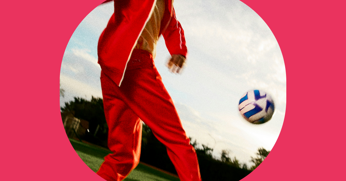 Iemand in een rood trainingspak die een bal trapt