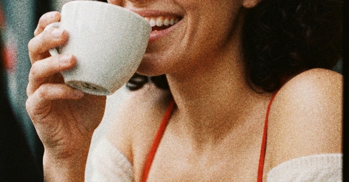 Vrouw die lachend uit een tas koffie drinkt