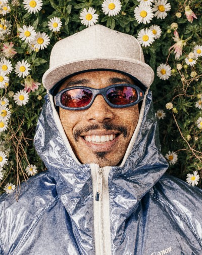 Man with sunglasses and a hood among flowers