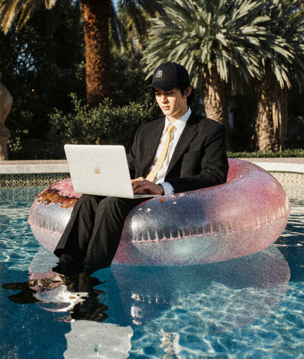 Man in a suit with a laptop on an inflatable ring in the pool